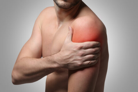 young,man,suffering,from,shoulder,pain,on,gray,background.,health